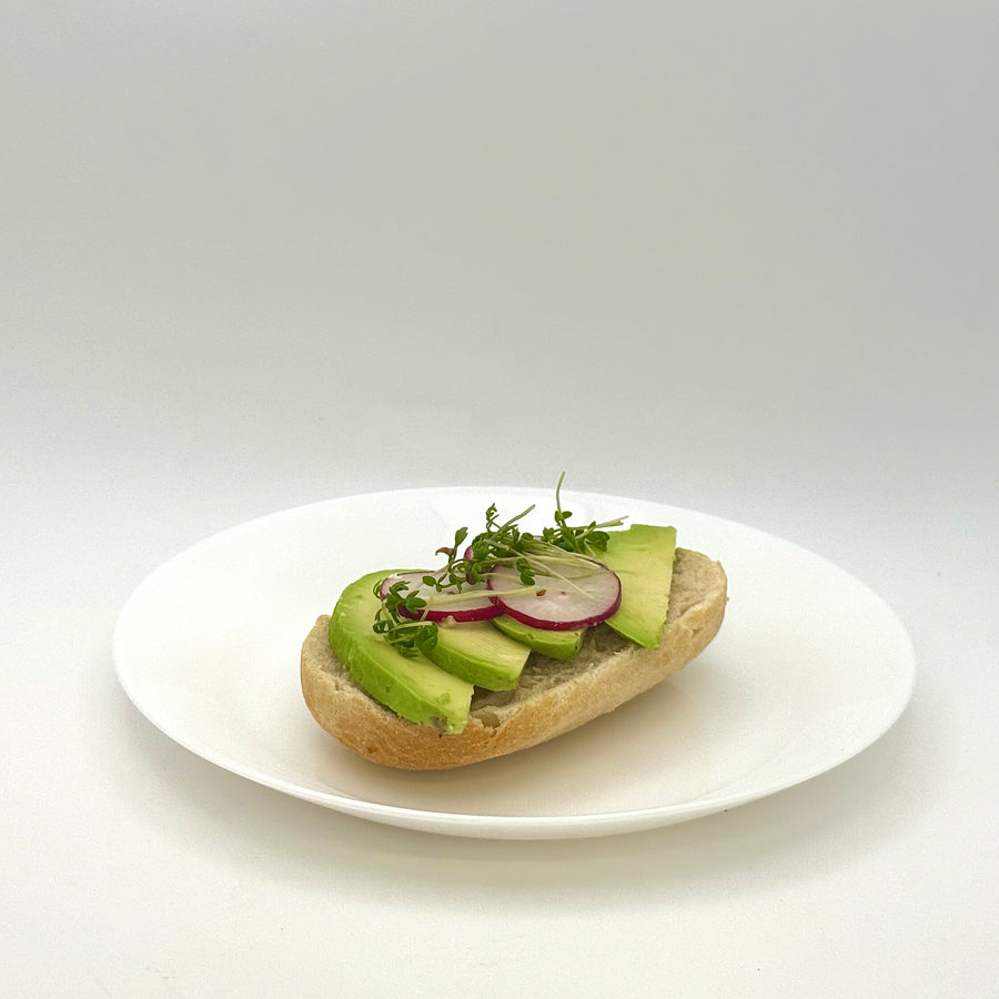 halbes belegtes Weizenbrötchen mit Avocado vegan